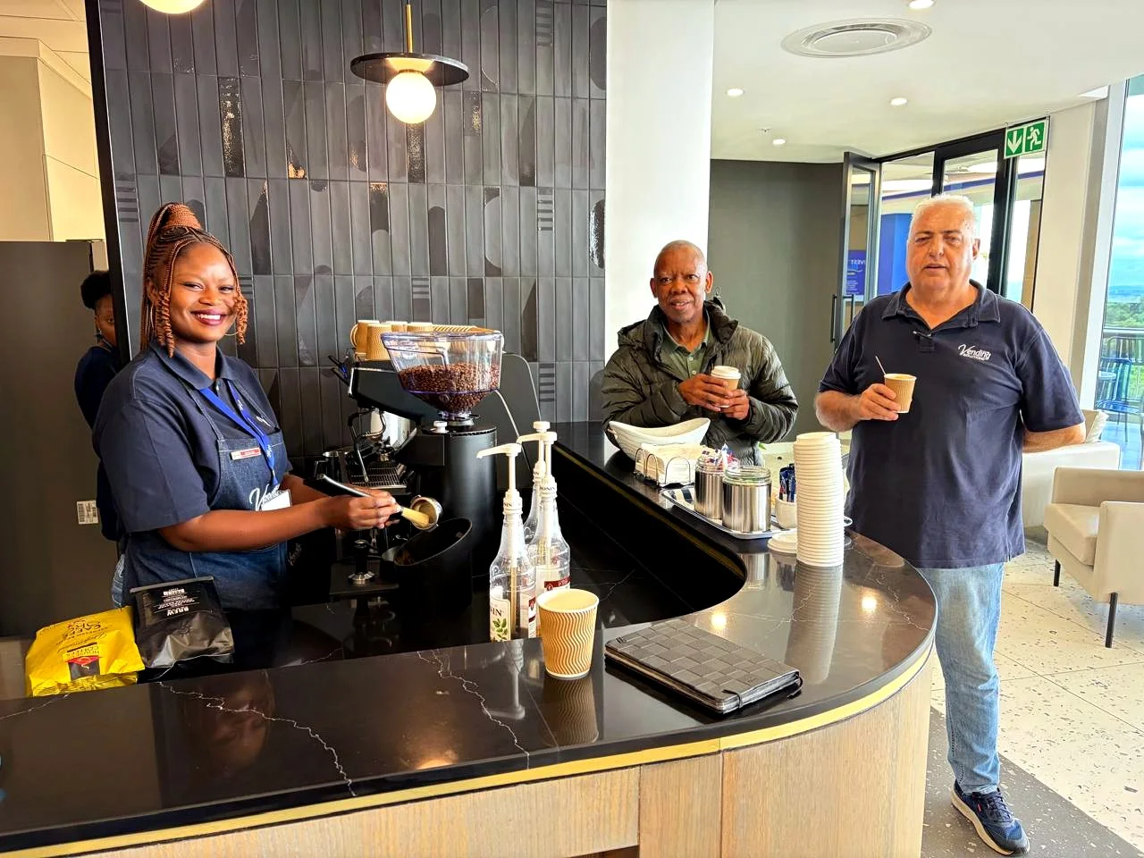 Barista serving fresh coffee to colleagues at an office coffee bar